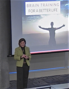 Dietitian Speaker Jennifer Neily stands ready to present in front of a screen that reads Brain Training for a Better Life.