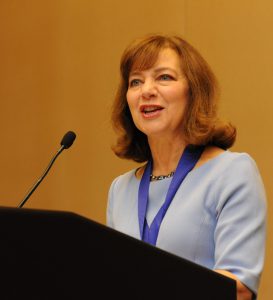 Dietitian Speaker Christine Palumbo stands behind a podium presenting enthusiastically.