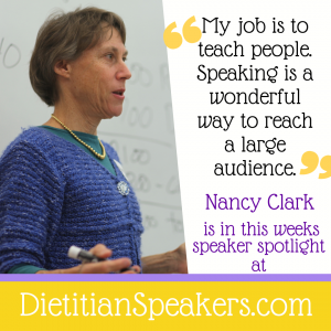 Dietitian Speaker Nancy Clark presents in front of a white board with a marker in her hand. She wears a blue top and necklace and is presenting on sports nutrition. 